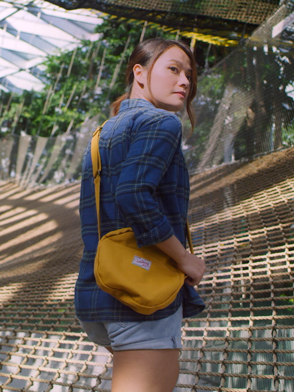 A girl with her hand on her bag, back facing the camera and showing her facial side profile.
